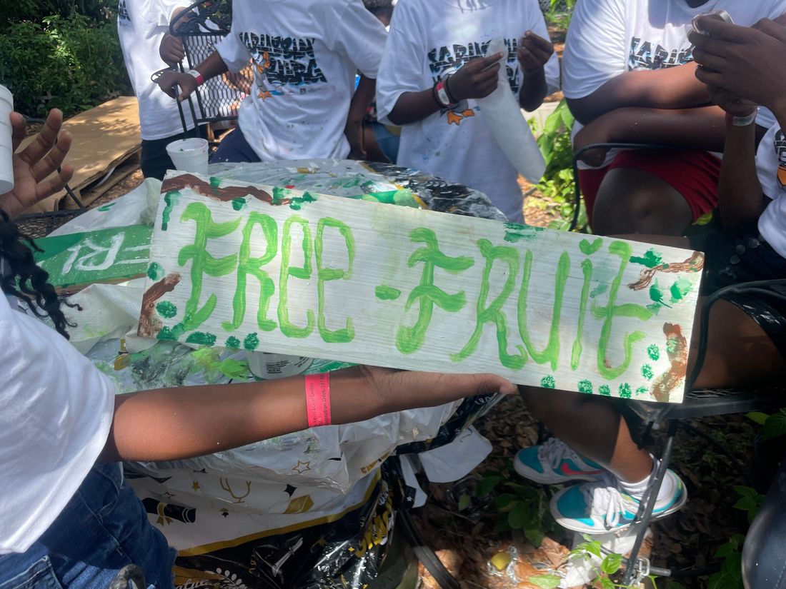 Volunteer Campers Paint and Display Signs saying "Free Fruit" for the community urban garden